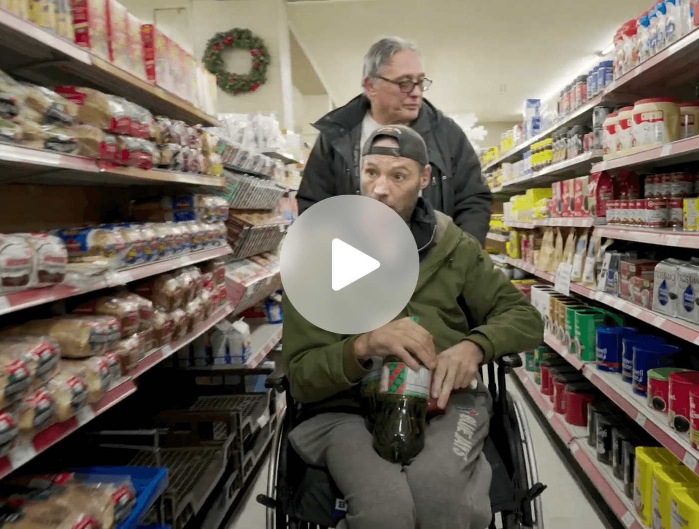 Caregiver assisting a person in a wheelchair at a grocery store