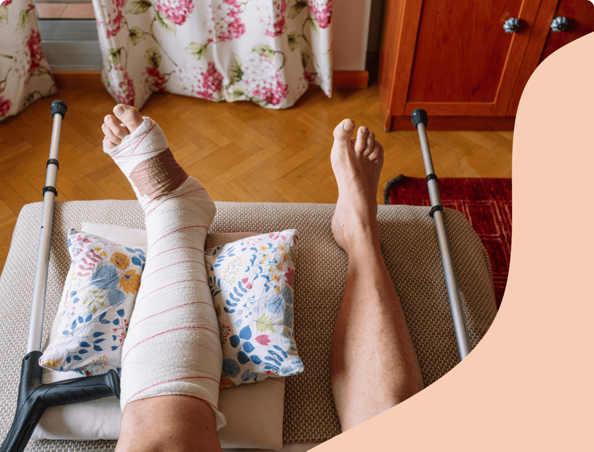 Person resting an injured leg on a pillow with crutches nearby
